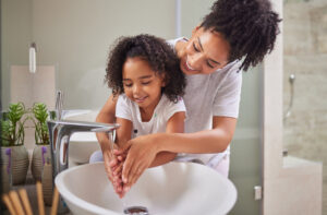 Mutter und Kind waschen sich die Hände, Infektions- oder Virenschutz im Badezimmer.