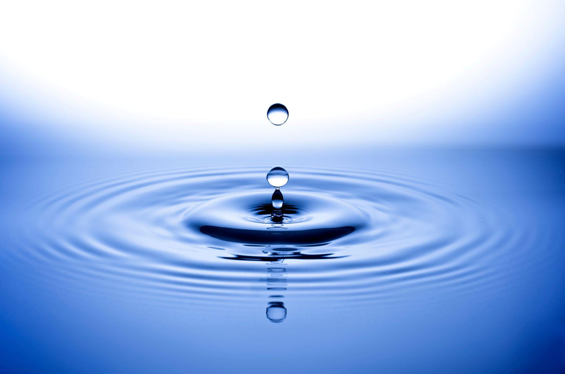 Wassertropfen über glatter Wasseroberfläche